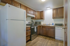 Una cocina con gabinetes de madera, un refrigerador blanco, un microondas, un horno y un lavavajillas.
