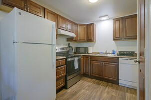 Una cocina con gabinetes de madera, un refrigerador blanco, un microondas, un horno y un lavavajillas.