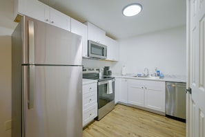 A modern kitchen with stainless steel appliances, white cabinetry, and a wooden floor. - Centrally Located Lacey Escape: 2 Mi to Hospital (Lacey)