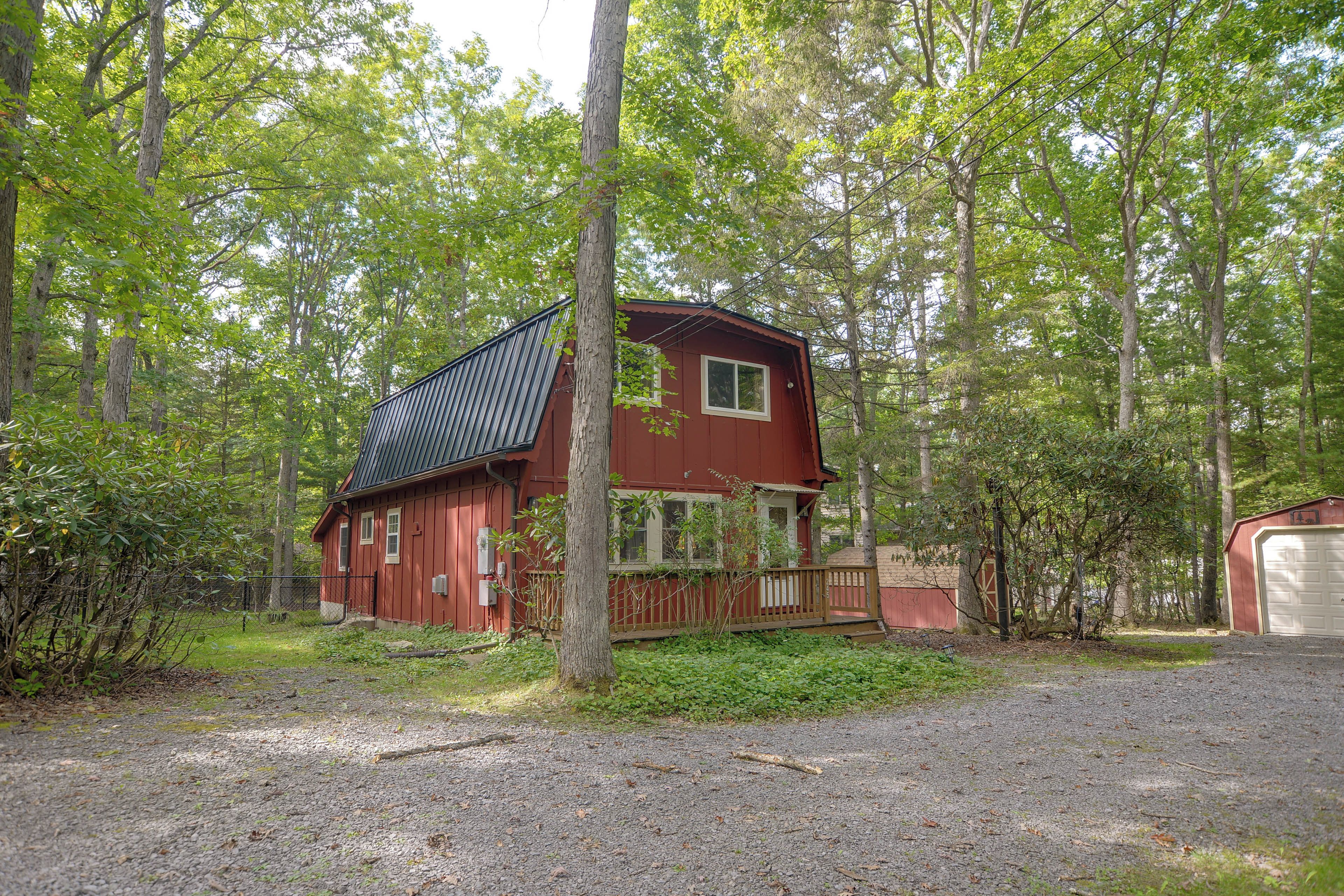 A red cabin with a sloped roof, surrounded by a forest.