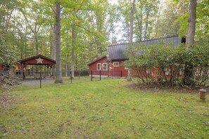 A fenced outdoor area with a small wooden structure and a red building with a metal roof. - Pet-friendly w/ Dock & Fenced-in Yard in Swanton (Swanton)