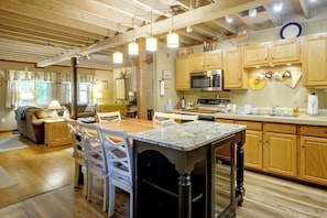 A spacious kitchen with wooden cabinets, a central island, and a dining area with chairs. - Pet-friendly w/ Dock & Fenced-in Yard in Swanton (Swanton)