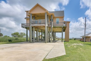 A two-story house with a balcony on the upper floor, supported by wooden stilts. - Sabine Lake Waterfront Retreat W/700' Lighted Pier (Port Arthur)