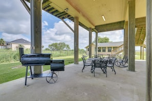 An outdoor patio with a grill, tables, and chairs.