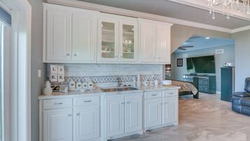 A spacious kitchen with white cabinetry, a marble backsplash, and a built-in oven.