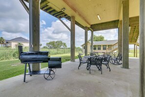 An outdoor patio with a grill, tables, and chairs.