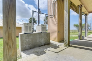 A concrete platform with two air conditioning units in front of a beige building with a door.