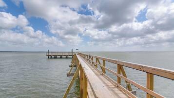 A wooden pier extending into calm water under a partly cloudy sky.