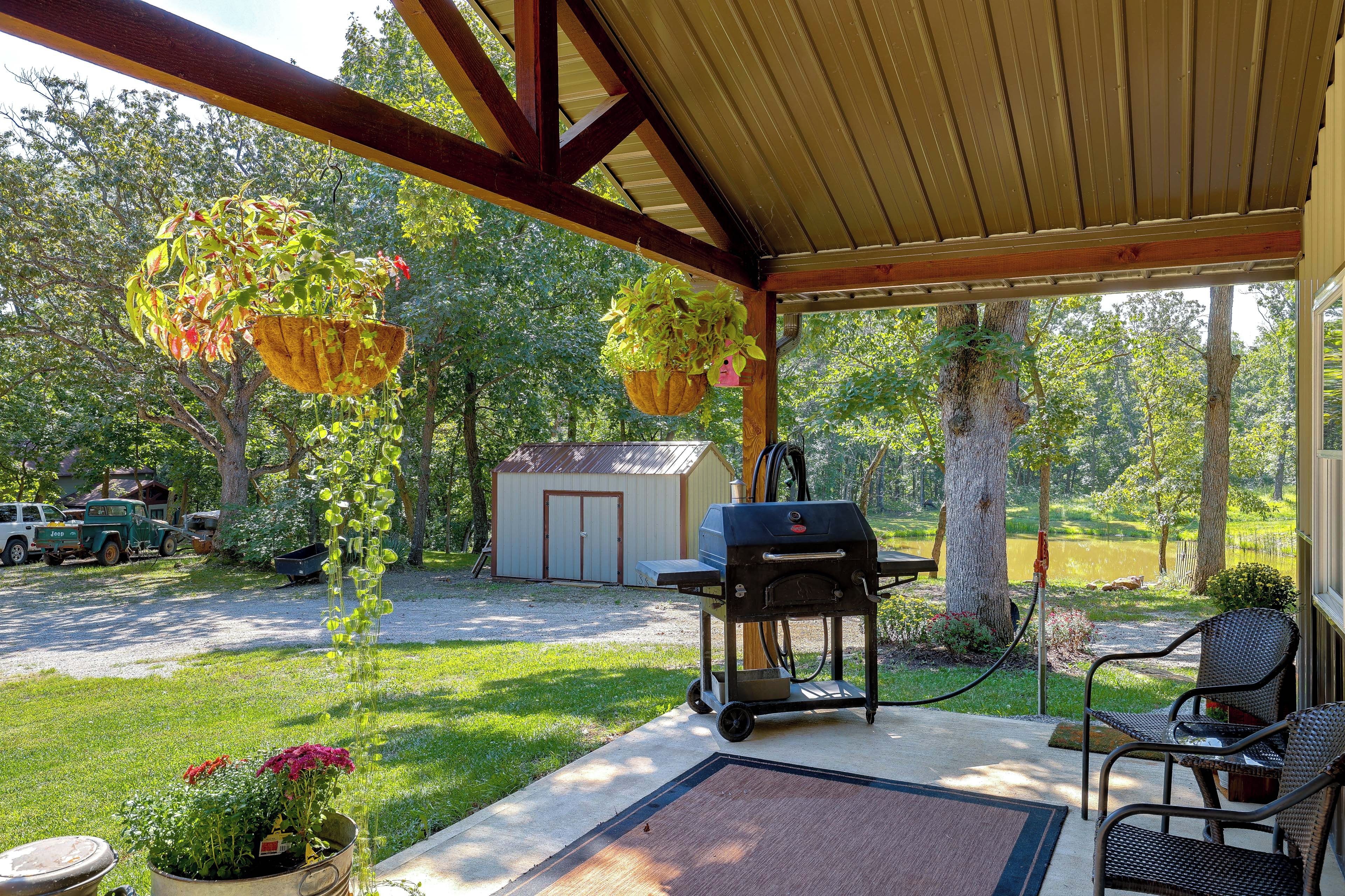 A covered patio with a grill, hanging plants, and a small shed.