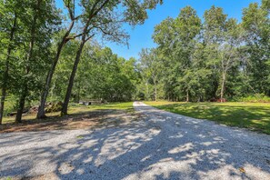 A gravel path leading through a wooded area with trees and a clear sky.
