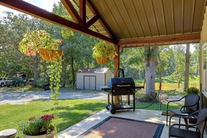 A covered patio with a grill, hanging plants, and a small shed.