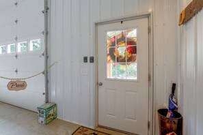 A garage door with a 'Private Please Do Not Enter' sign, a window with a decorative wreath, and a bucket with a blue tarp.