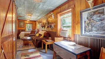 A cozy cabin interior with a wooden interior, a dining area, and a large window providing a view of the outdoors.