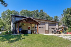 A two-story building with a garage, a covered porch, and a vehicle in the driveway. - Countryside Escape! Cozy Studio w/ Patio (Chillicothe)
