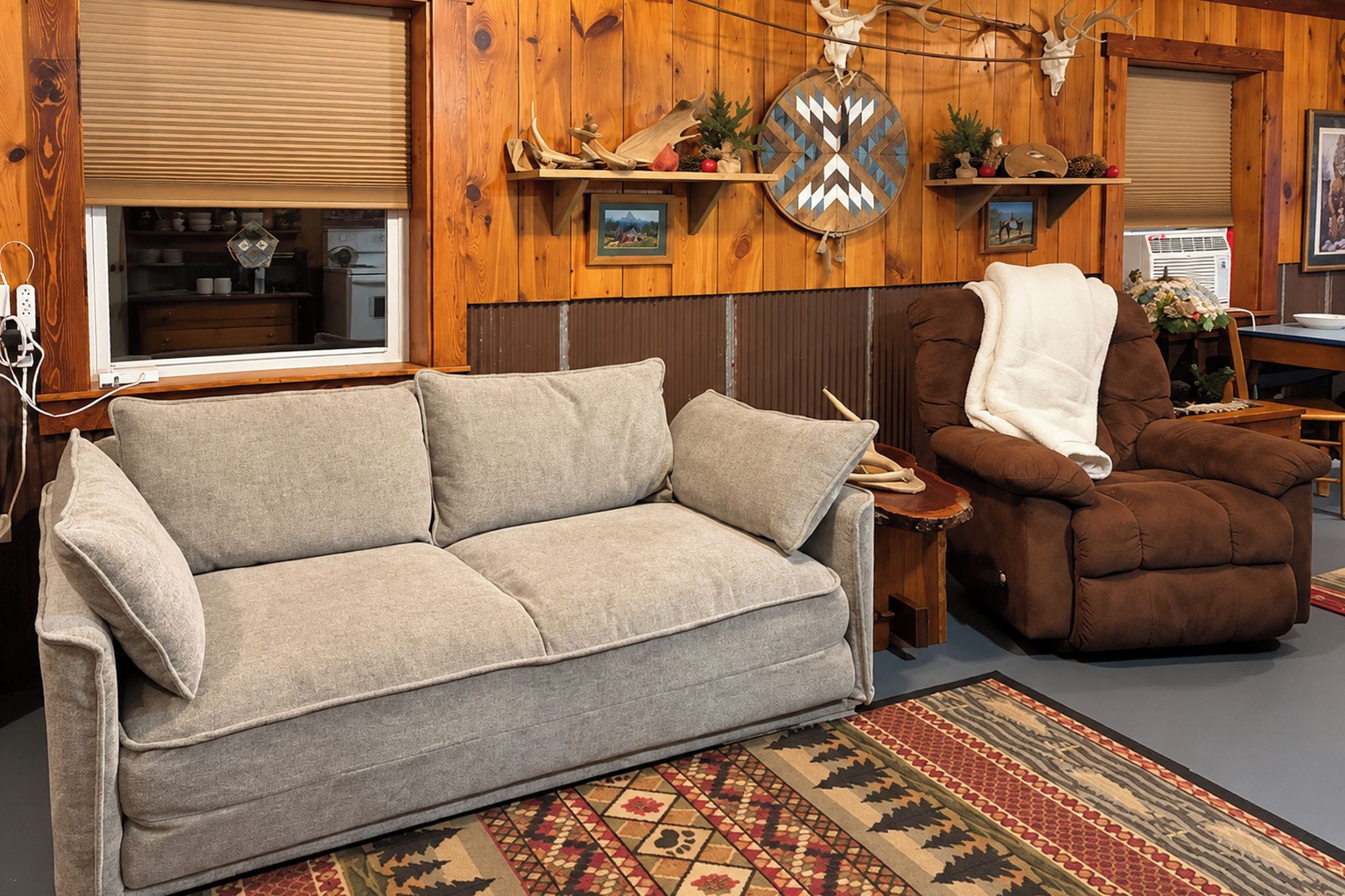 A cozy living room with a sofa, armchair, and a patterned rug.