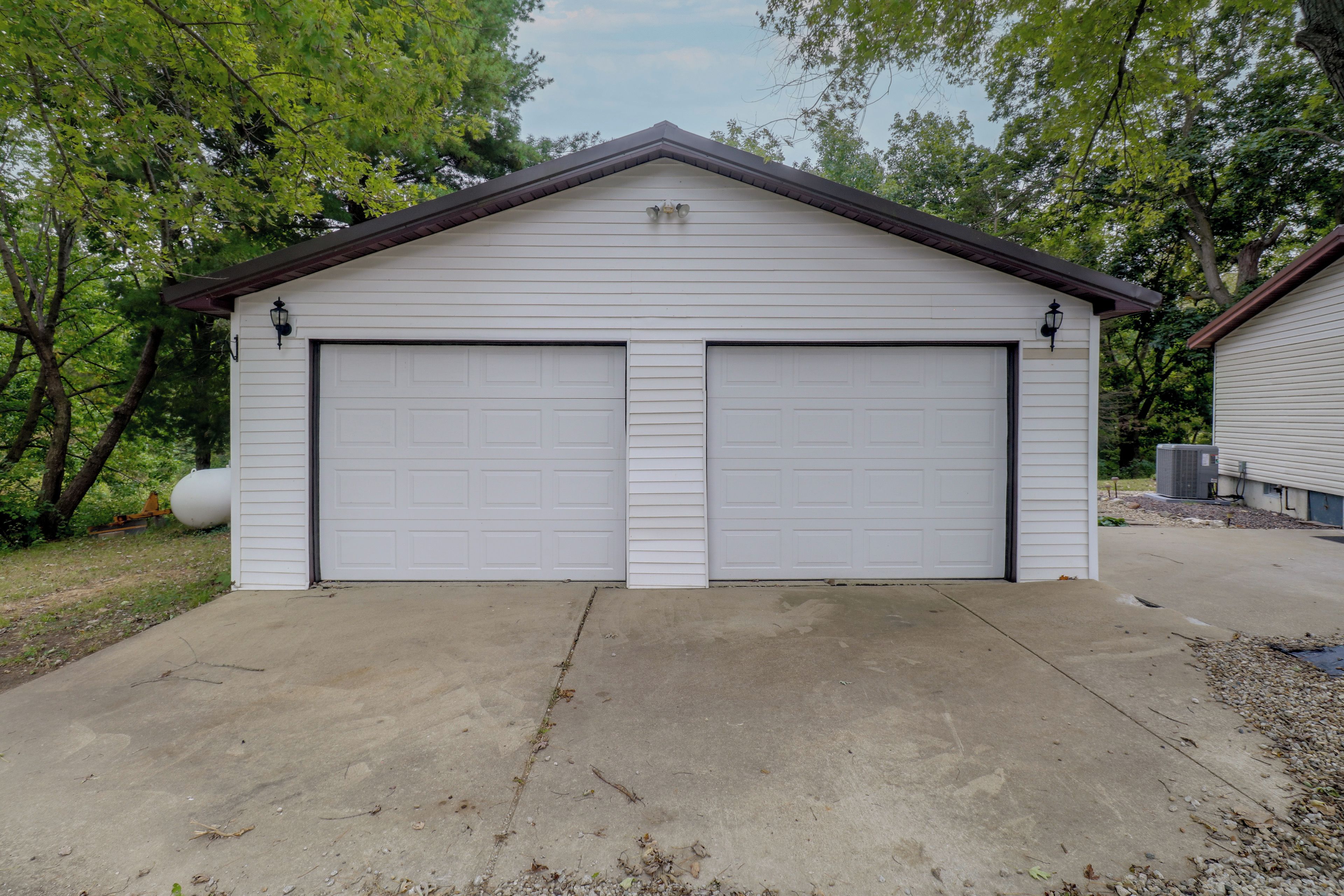 Un garage pour deux voitures, doté d’un toit à pignon et d’une allée en béton.