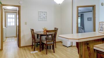 A dining area with a wooden table and chairs, a white ceiling light, and a welcome sign on the wall.