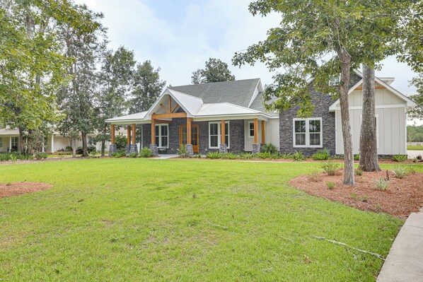 A residential house with a stone facade, a covered porch, and a well-maintained lawn.