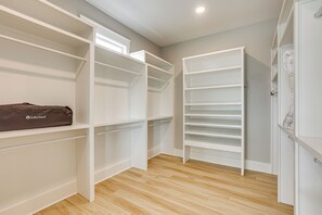 A walk-in closet with open shelving, a hanging rod, and a coat rack.