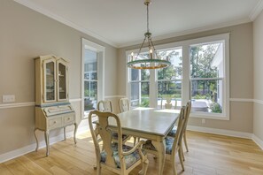 A dining room with a large table, chairs, a chandelier, and a cabinet.