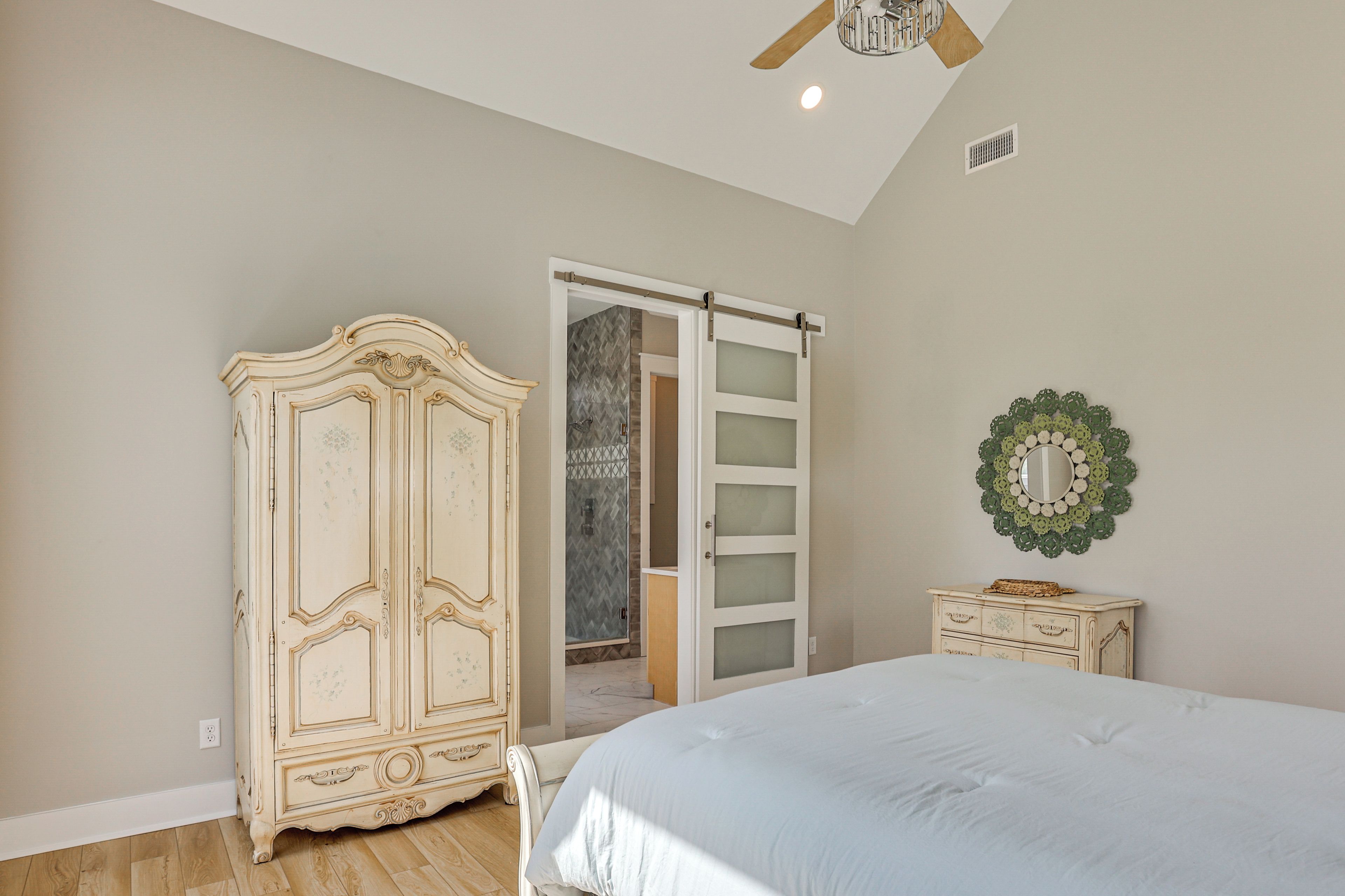A bedroom with a bed, a wardrobe, a door leading to a bathroom, and a ceiling fan.