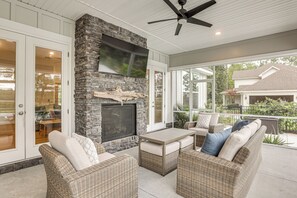 A covered patio with wicker furniture, a stone fireplace, and a ceiling fan. - Pool & Hot Tub at Gated Waverly Home (Waverly)