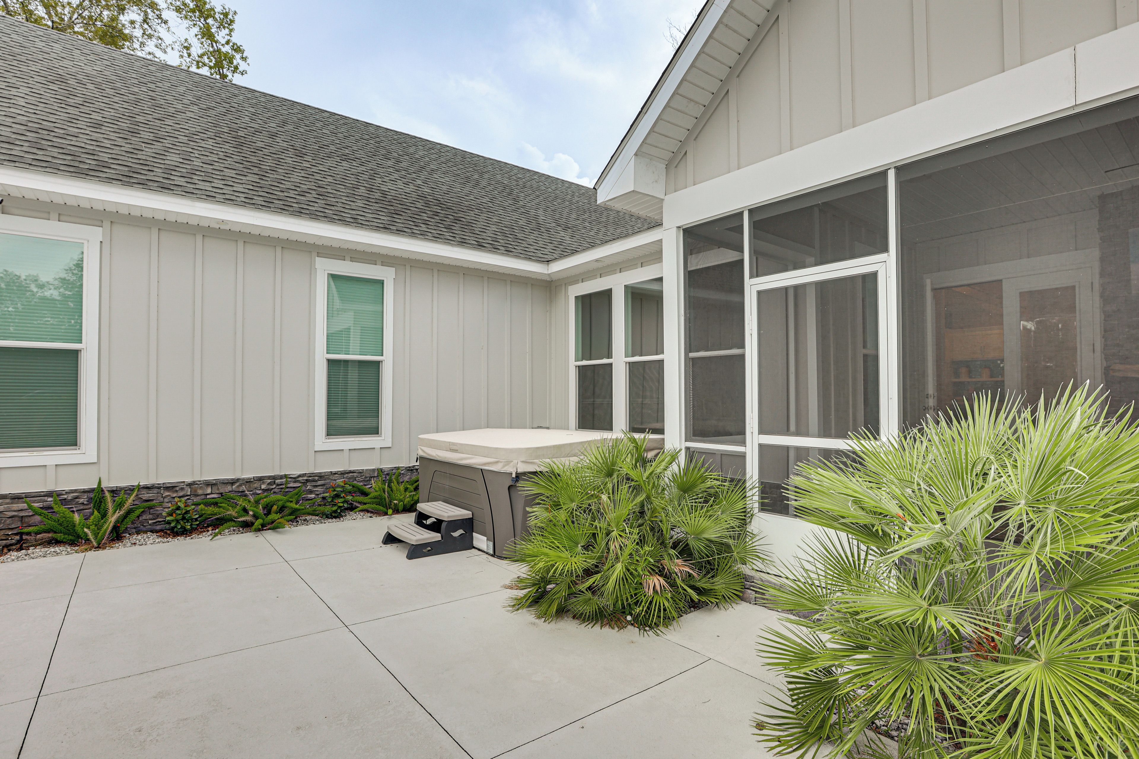 A residential building with a covered patio, a hot tub, and a variety of plants.