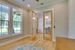 A hallway with wooden flooring, a glass door, and a view of a garden through a large window.