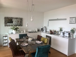 Eine moderne Küche mit Essbereich, weißen Schränken und einer zentralen Kochinsel mit Spüle.