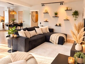 Ein modernes Wohnzimmer mit einer Eckcouch, einem Couchtisch und Zimmerpflanzen.