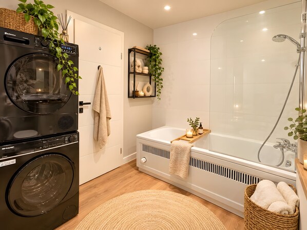 Ein modernes Badezimmer mit Waschmaschine, Badewanne und Dusche.