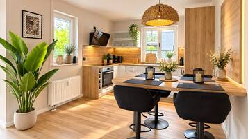 Eine moderne Küche mit Essbereich, Holzboden und schwarzen Barhocker.