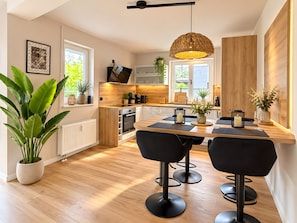 Eine moderne Küche mit Essbereich, Holzboden und schwarzen Barhocker.