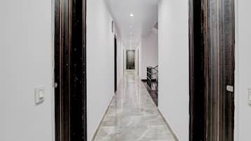 Un pasillo con suelo de mármol, paredes blancas y puertas de madera oscura.