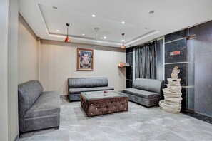 A modern living room with grey sofas, a glass coffee table, and a decorative statue.