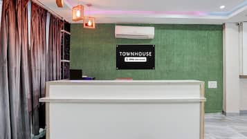Un mostrador de recepción con un letrero que dice 'TOWNHOUSE OYO-Serviced' frente a una pared verde.