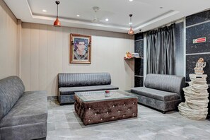 A modern living room with grey sofas, a glass coffee table, and a decorative statue.