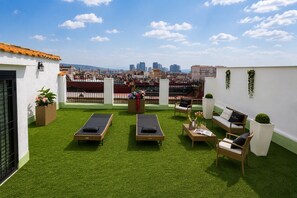 A rooftop terrace with artificial grass, two sun loungers, a sofa, and a small table with drinks. - [Historic Center and Jacuzzi] Sedil Capuano Terrace (Napoli)