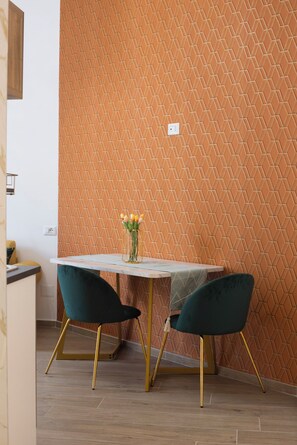 A dining area with a table and two chairs, a vase with flowers, and a textured wall. - [Historic Center and Jacuzzi] Sedil Capuano Terrace (Napoli)