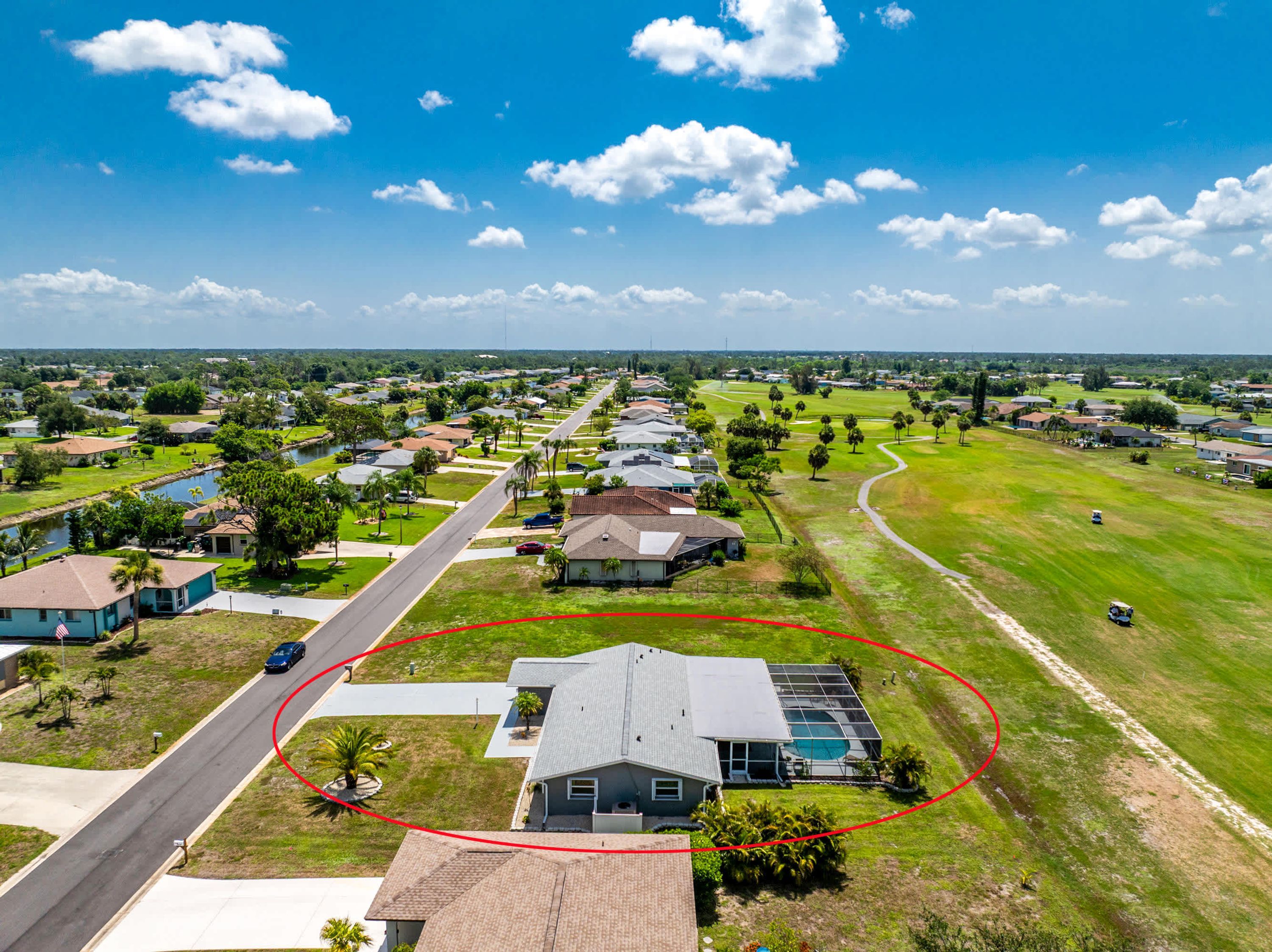 A residential area with houses, a road, and a golf course.