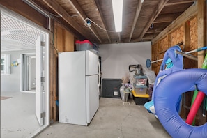 A compact utility room with a white refrigerator, a blue inflatable ring, and a broom leaning against the wall. - Dreams Away - Sleeps 10 Pool Golf Fun (Rotonda West)