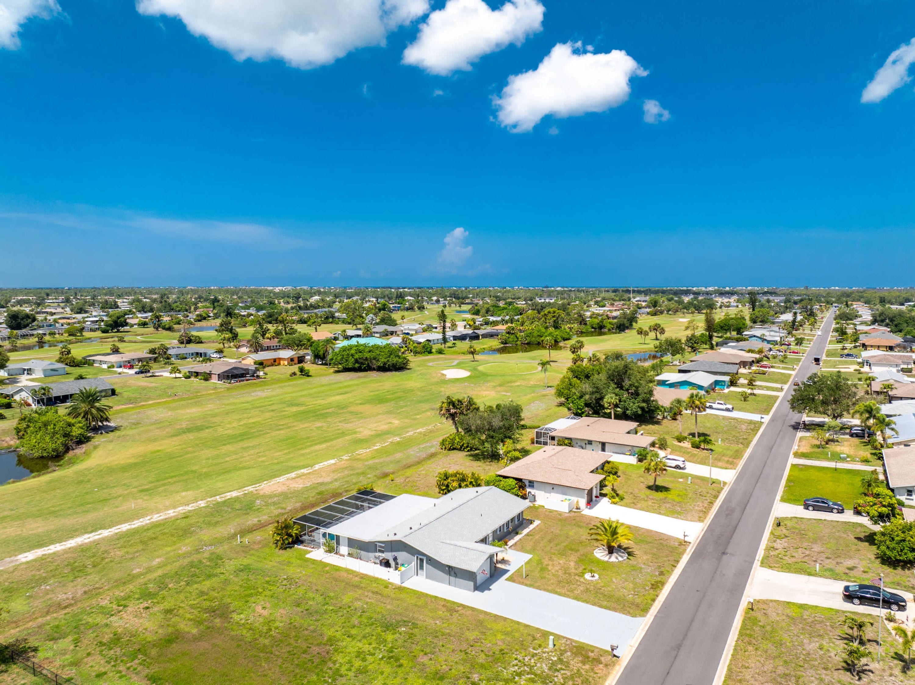 Área residencial com casas, uma estrada e um campo de golfe.