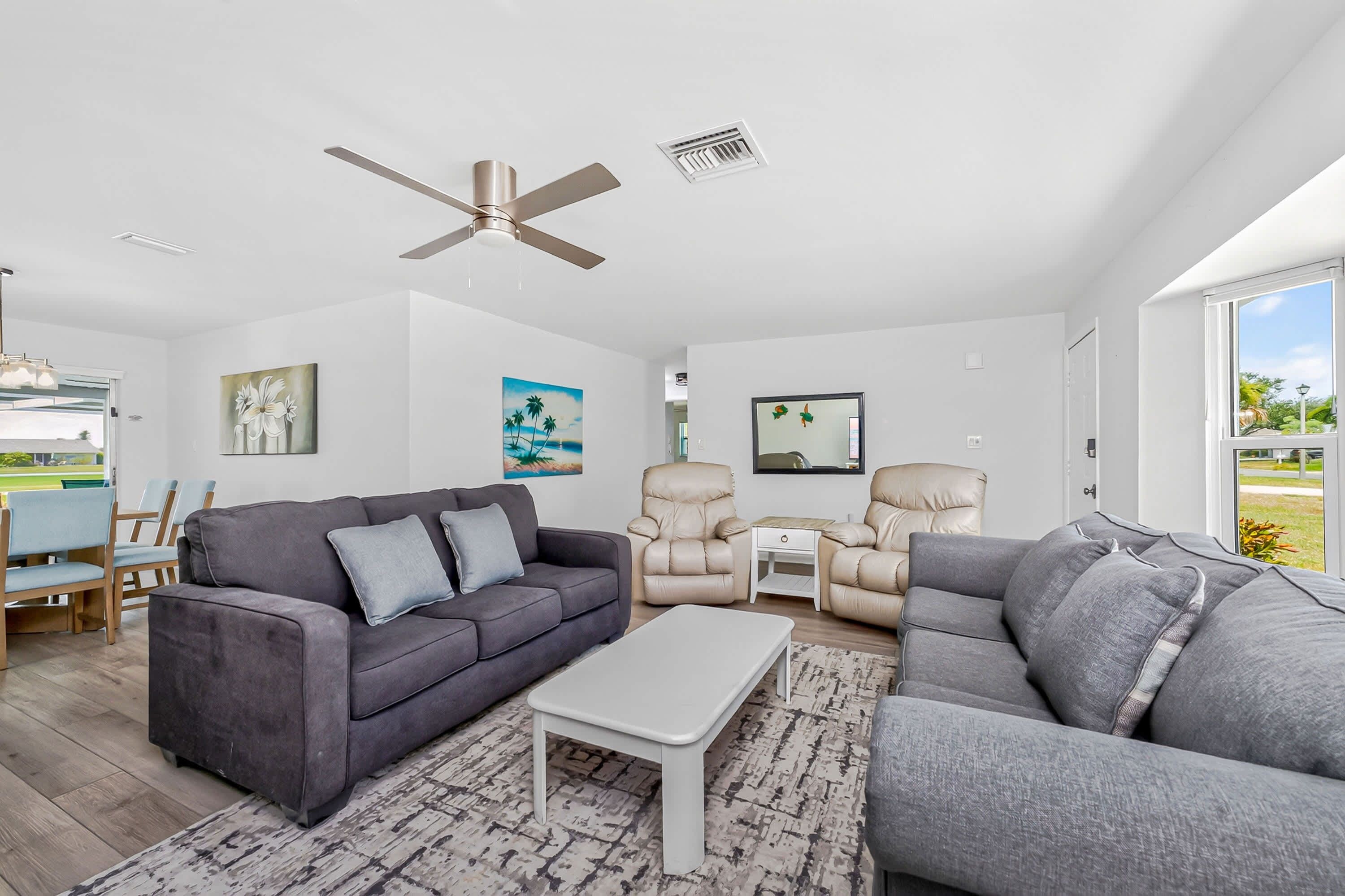A modern living room with a grey sofa, a white coffee table, and a ceiling fan.