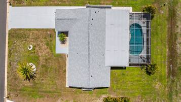 Luchtbeeld van een gebouw met een plat dak, een zwembad en omliggend groen.