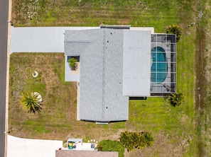 Vista aérea de un edificio con techo plano, piscina y vegetación circundante.