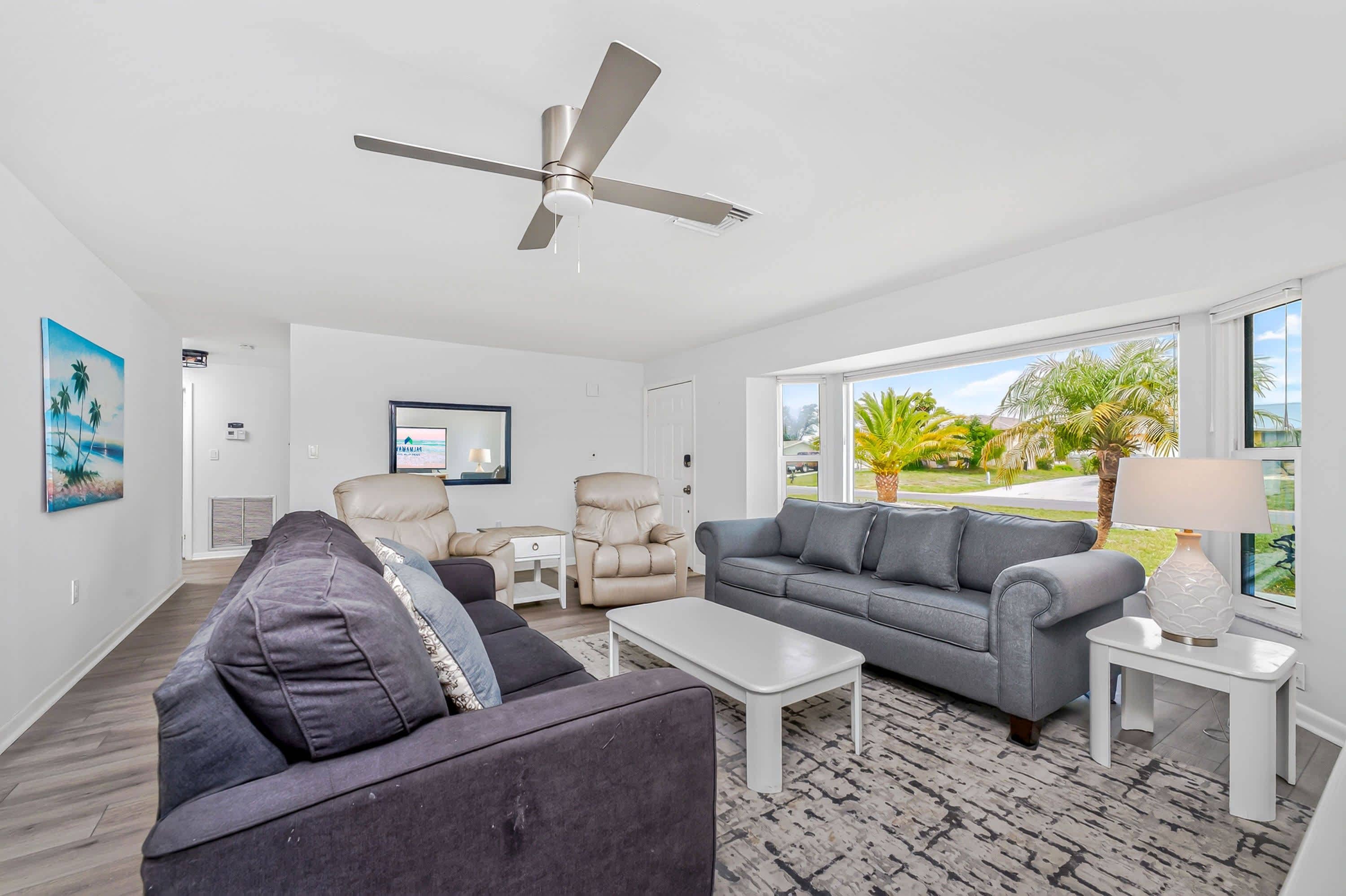A modern living room with a ceiling fan, two sofas, a coffee table, and a TV.