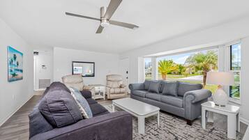 A modern living room with a ceiling fan, two sofas, a coffee table, and a TV.