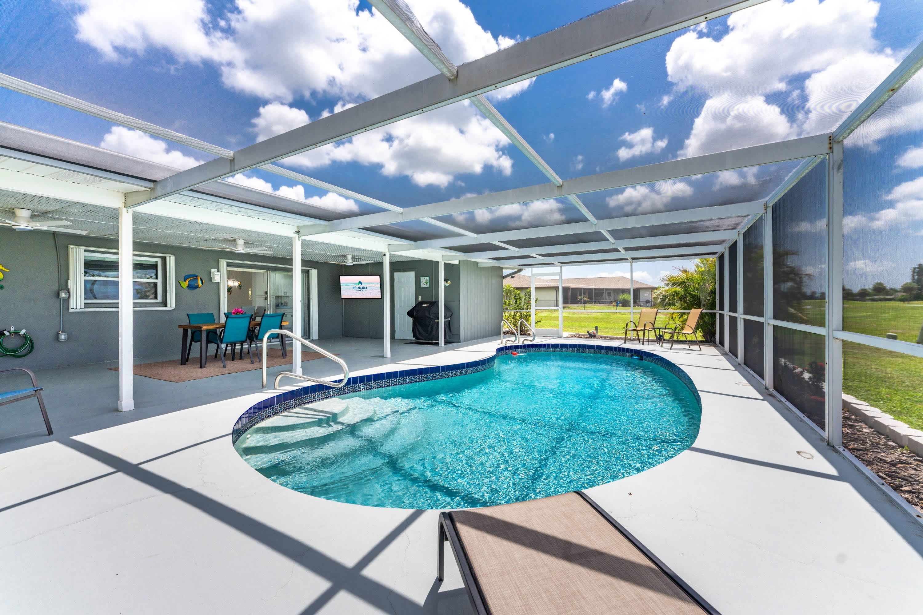 Piscina techada con vista al cielo y un área verde al fondo.