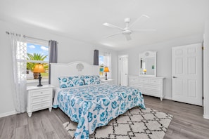 A bedroom with a bed, two bedside tables, a ceiling fan, a window with curtains, a dresser, and a rug. - Dreams Away - Sleeps 10 Pool Golf Fun (Rotonda West)