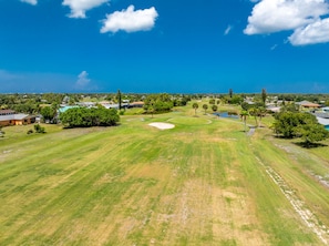 A golf course with a clear sky, surrounded by residential buildings and greenery. - Dreams Away - Sleeps 10 Pool Golf Fun (Rotonda West)